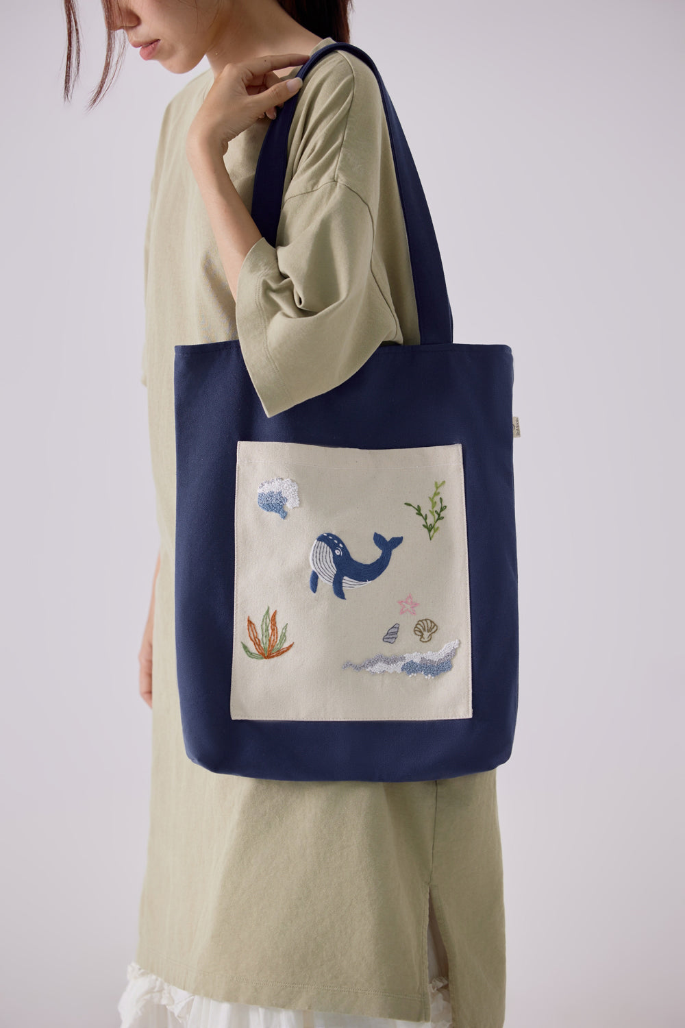 Woman carrying navy tote bag with whimsical ocean-themed embroidery