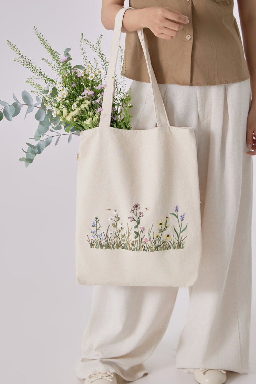 Botanical Garden Embroidery Tote Bag with floral design, styled with casual outfit and filled with fresh greenery. Ideal for eco-conscious fashion lovers.