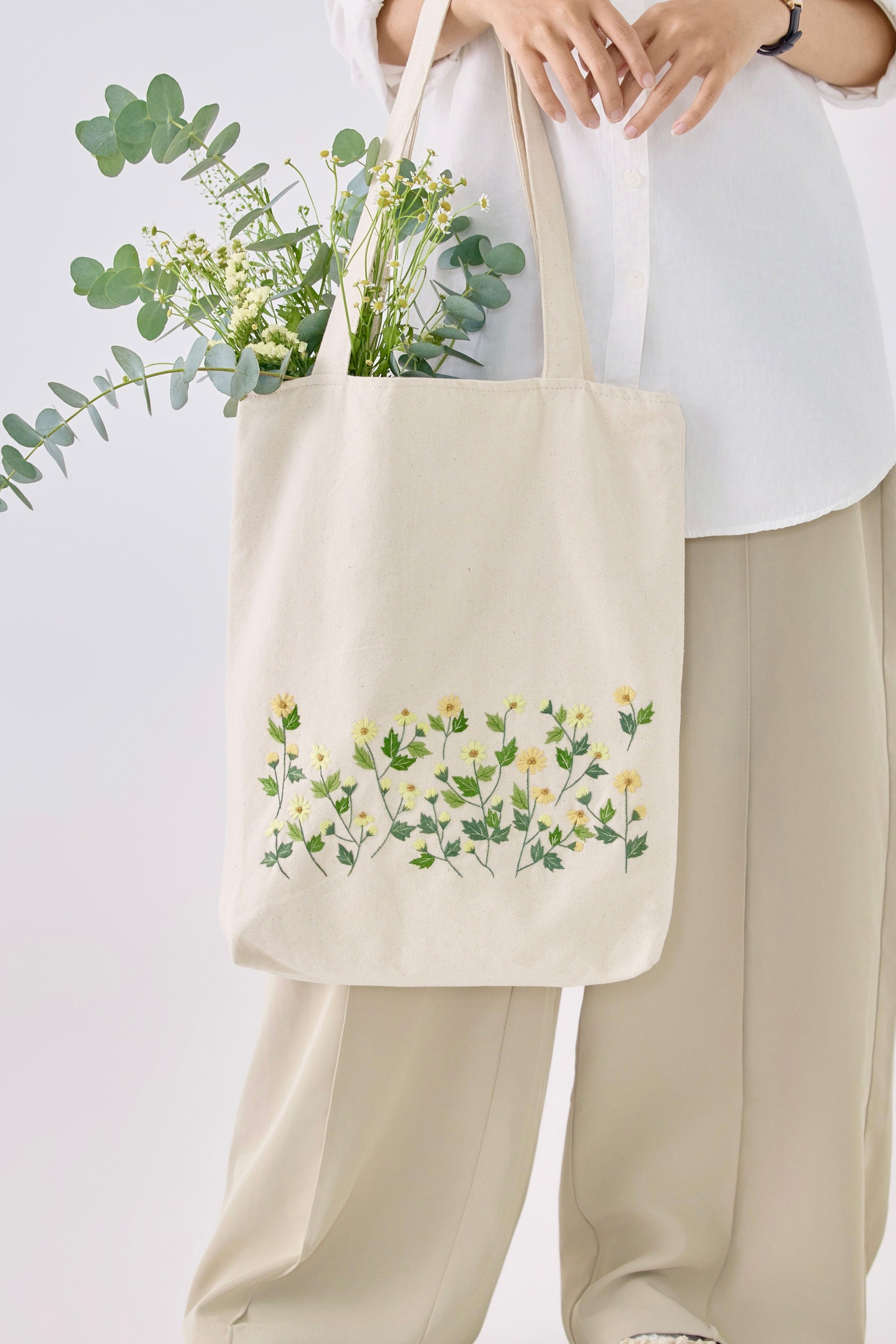 Yellow Daisy Embroidery Tote Bag held by model, showcasing floral embroidery and spacious design for everyday use in apparel accessories.