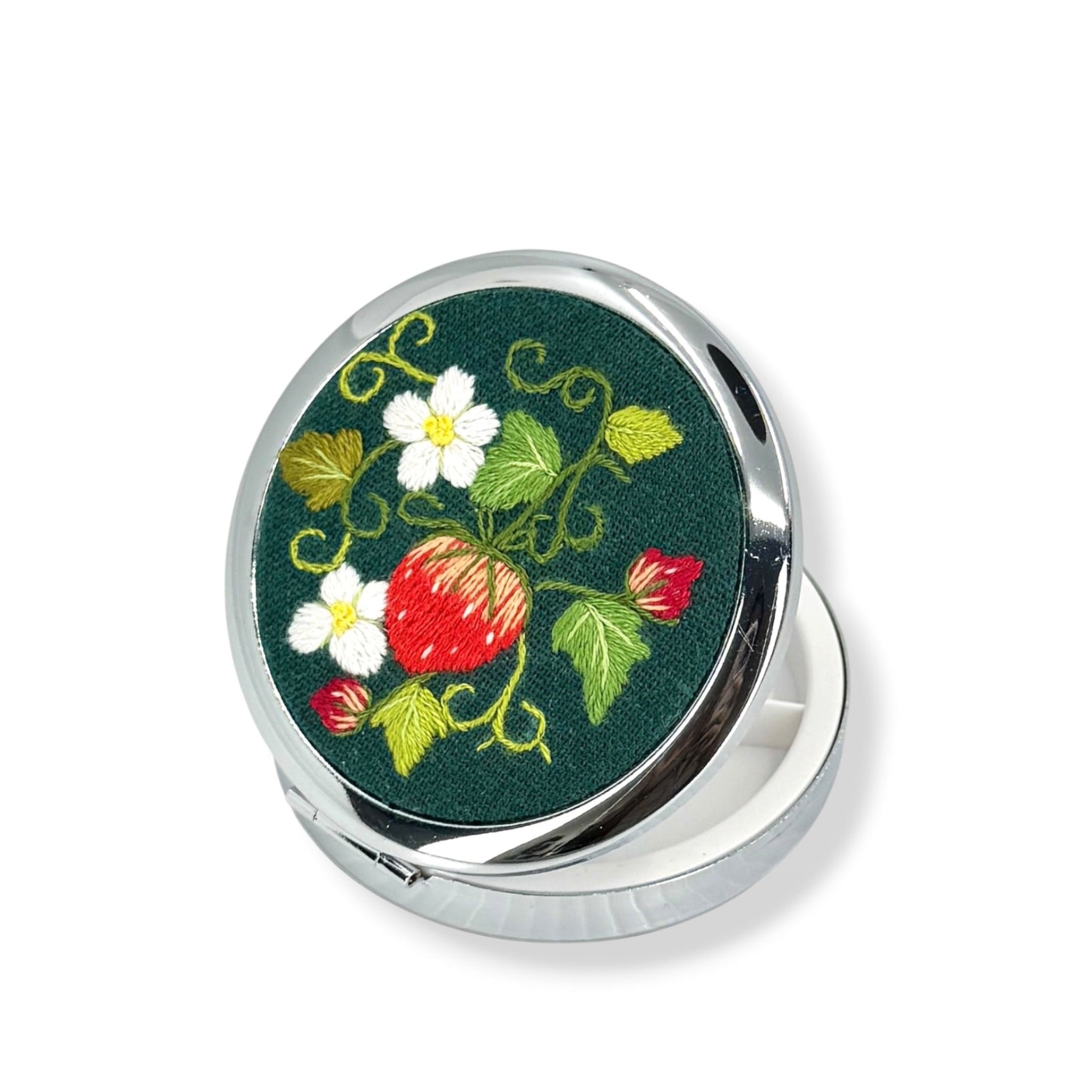 Round compact mirror with floral design on a green background