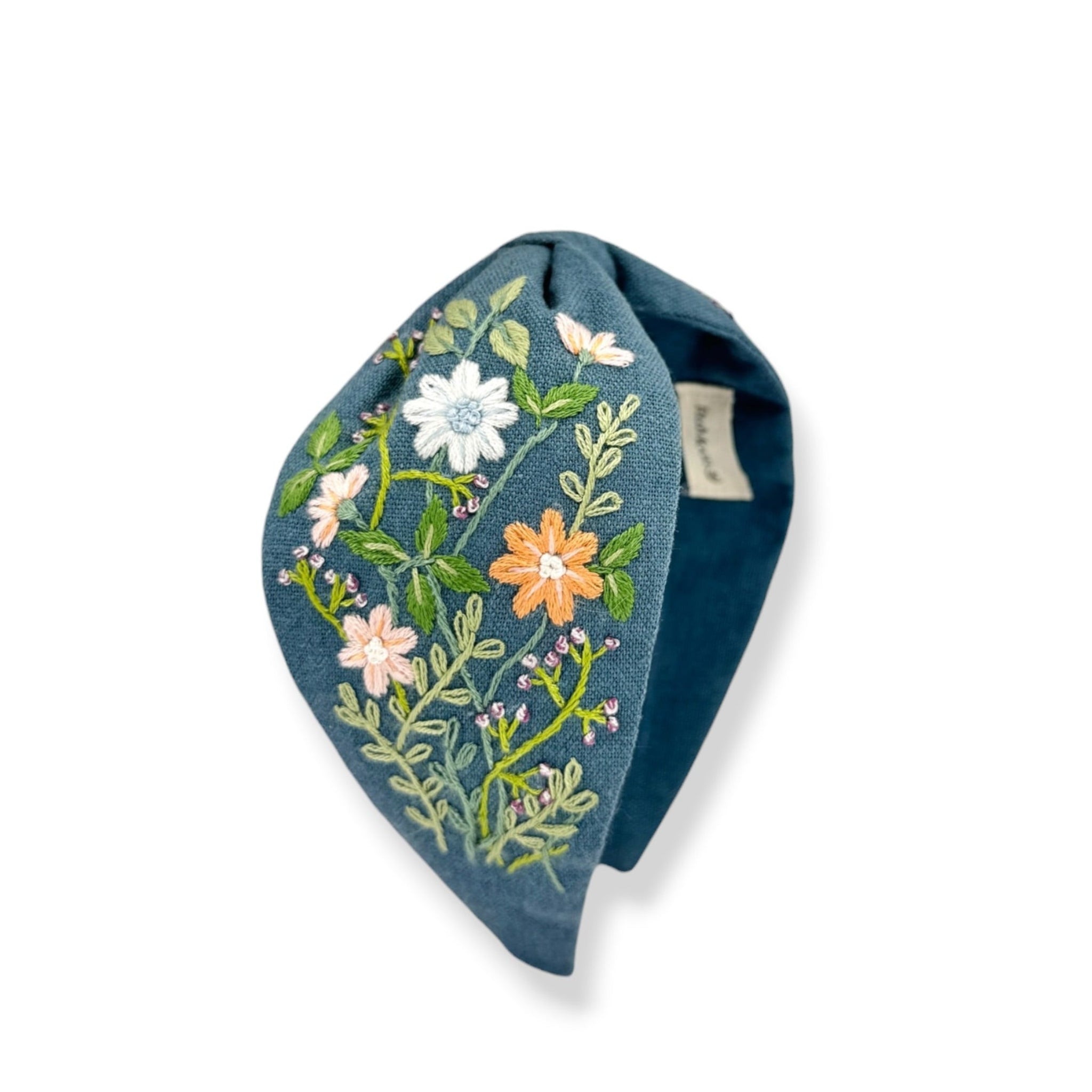 A blue denim-style headband featuring colorful floral embroidery with white, orange, and pink flowers and green leaves, shown on a plain white background.