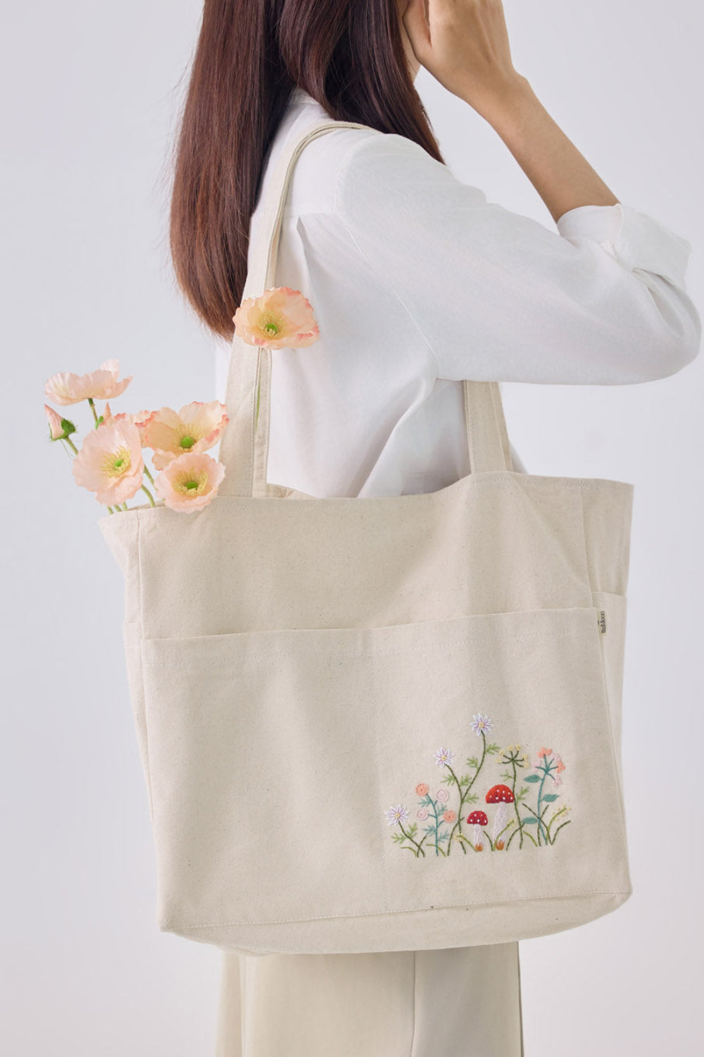 Mushroom Multiple Pockets Hand Embroidery White Tote Bag with floral and mushroom stitching, worn over shoulder, ideal for everyday use.