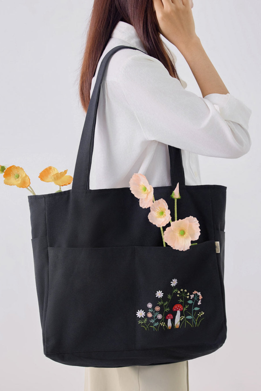 Mushroom Multiple Pockets Hand Embroidery Black Tote Bag with floral embroidery, worn on shoulder, ideal for everyday use and travel organization.