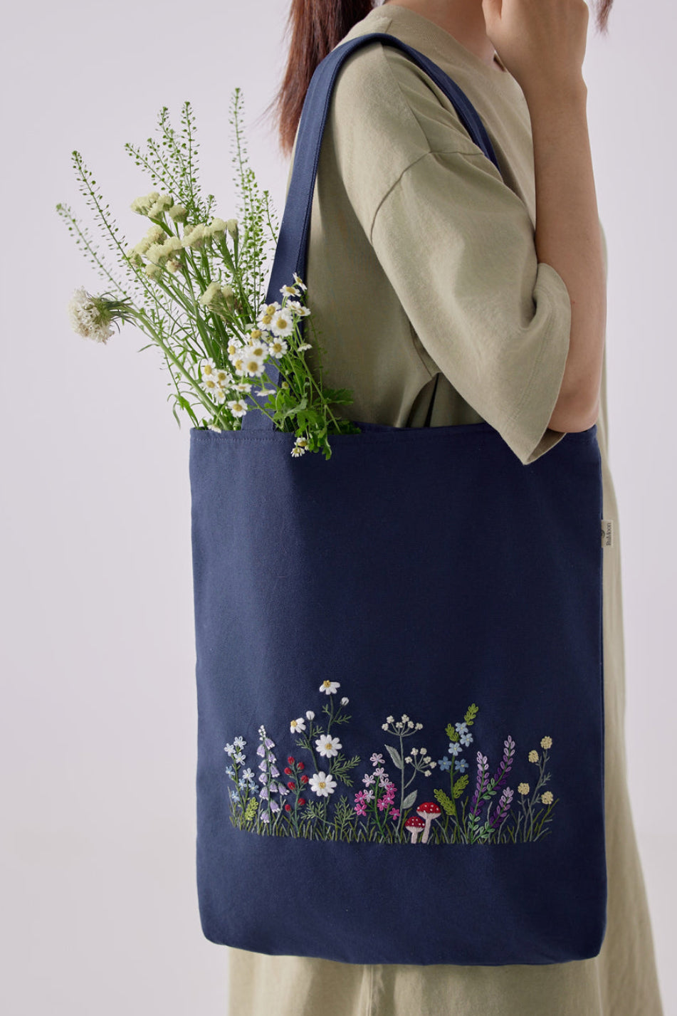 Wildflowers Garden Embroidery Tote Bag in navy blue with colorful floral embroidery, styled with fresh flowers, ideal for casual outfits.